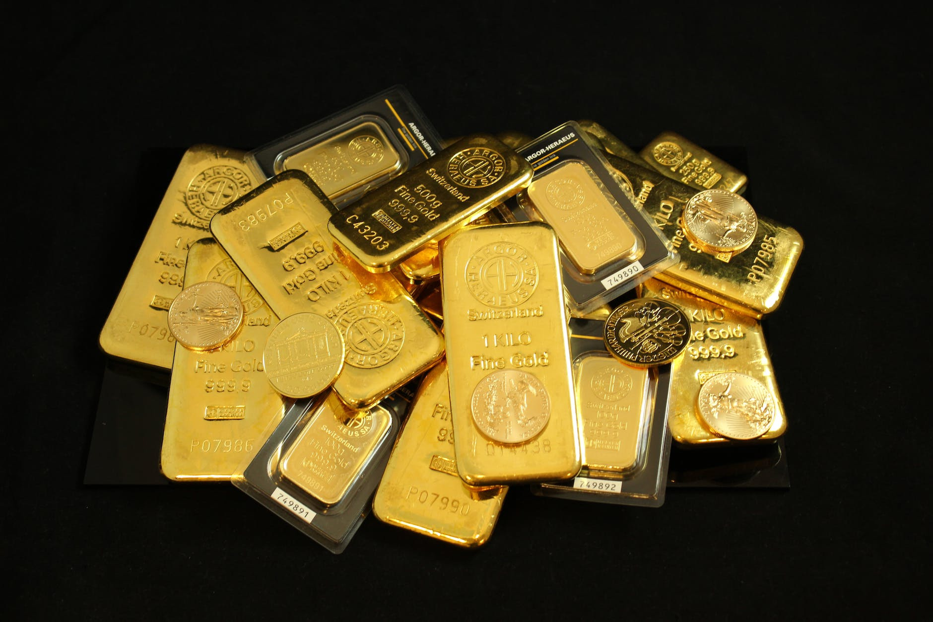gold bars and coins on a black surface
